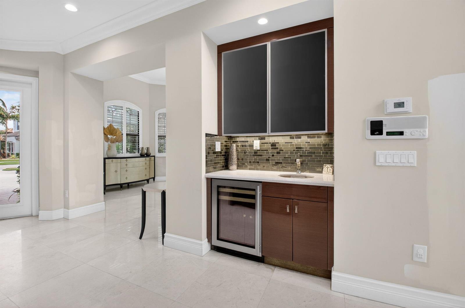 A wet bar with dark wood cabinets, a wine cooler, and a tiled backsplash — 16801 Pavilion Way, Delray Beach FL 33446, DELRAY BEACH, FL