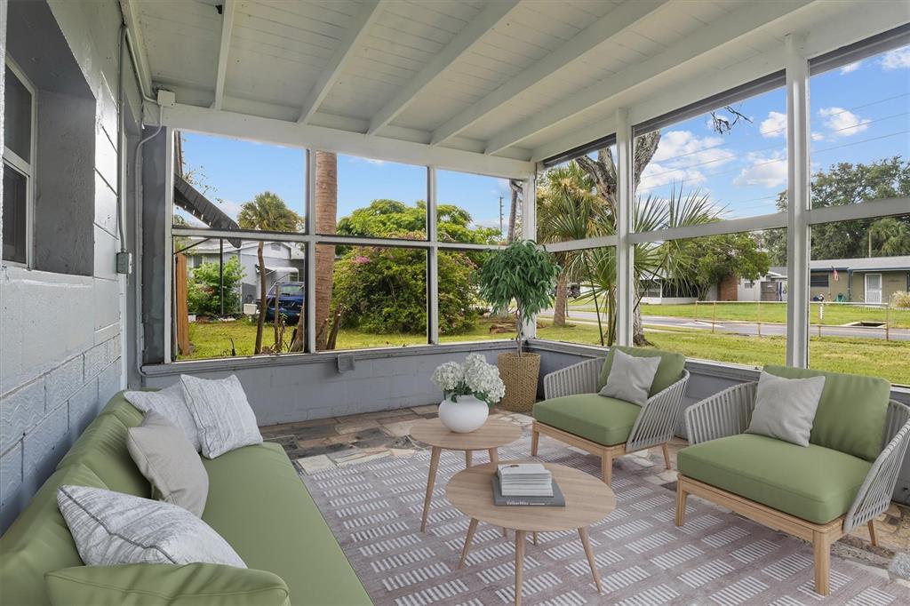 A screened-in porch features green patio furniture, a patterned rug, and views of a yard — 6723 78TH AVENUE N, PINELLAS PARK, FL