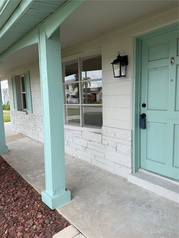 A covered porch features a light green front door, a matching support column, and stone siding — 13423 SUSAN DRIVE, HUDSON, FL