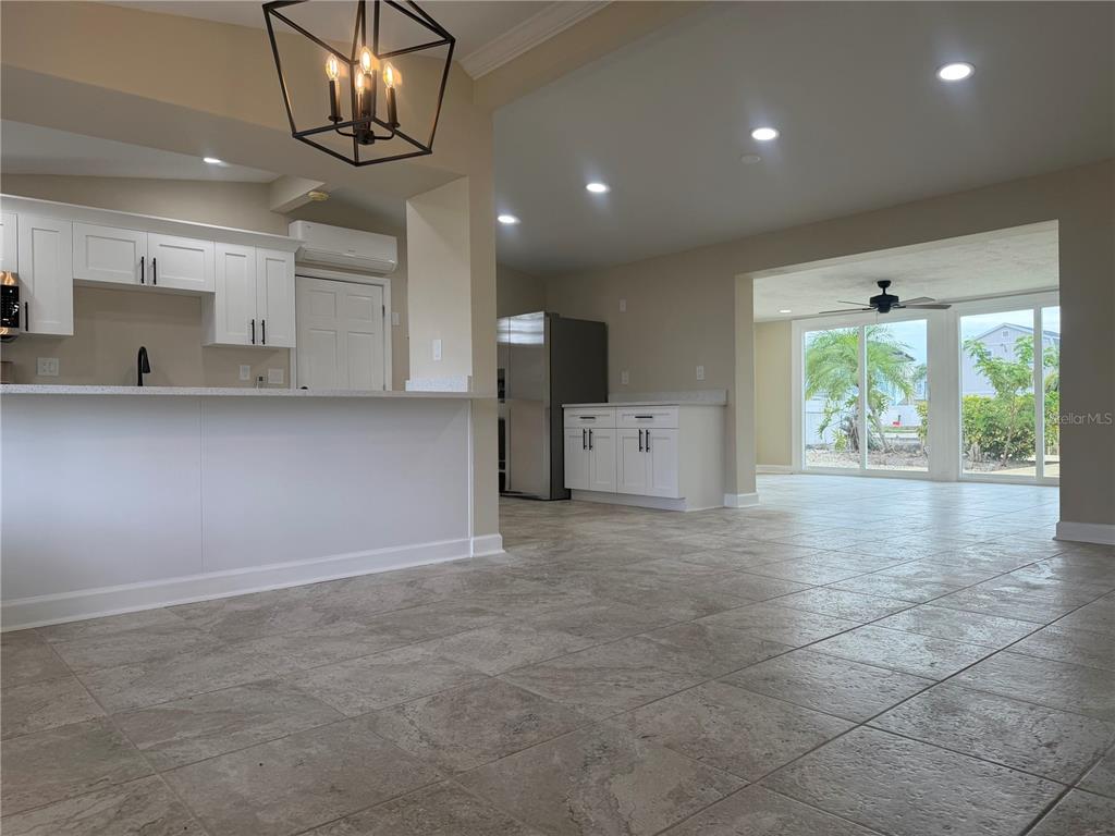 A kitchen with white cabinets and a breakfast bar opens into a tiled living area — 13423 SUSAN DRIVE, HUDSON, FL