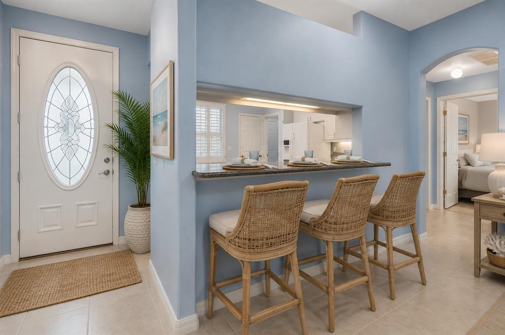 A light blue entryway features a breakfast bar with three wicker stools and a front door — 26903 HONEYMOON AVENUE, LEESBURG, FL