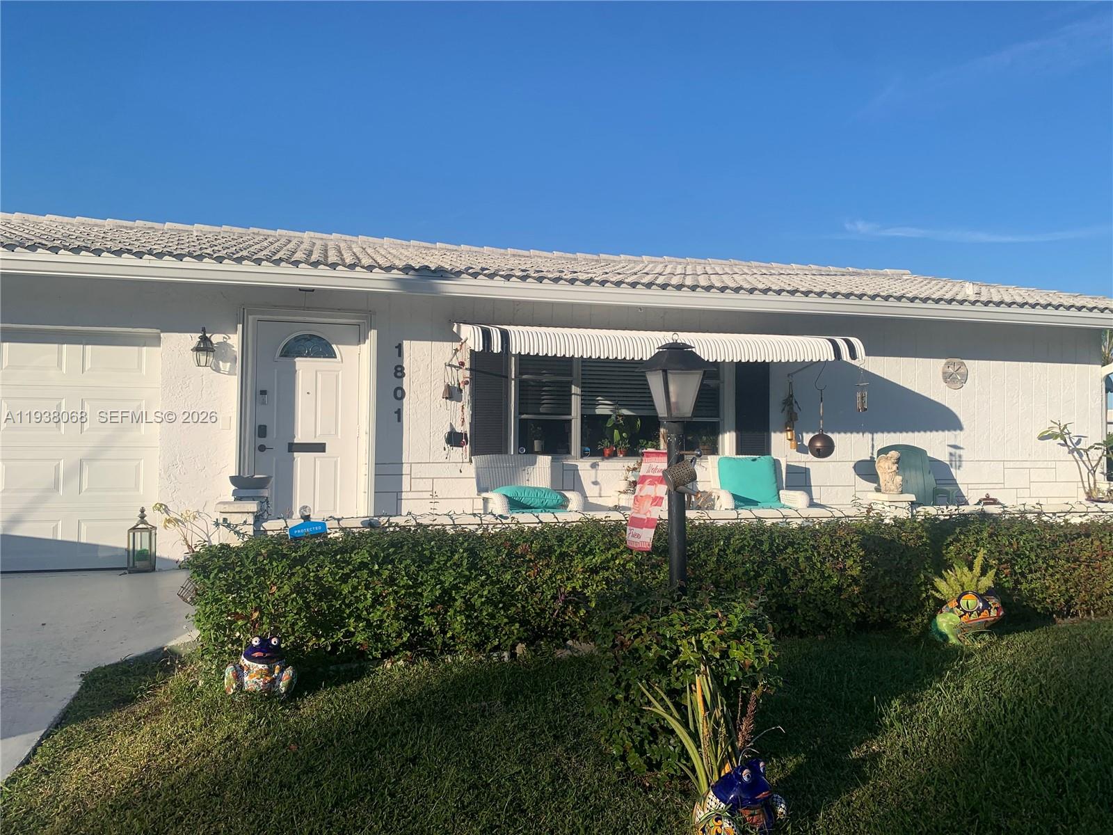 A white single-story house features a tiled roof, a front porch, and a manicured hedge — 1801 SW 22nd Way, Boynton Beach FL 33426, BOYNTON BEACH, FL