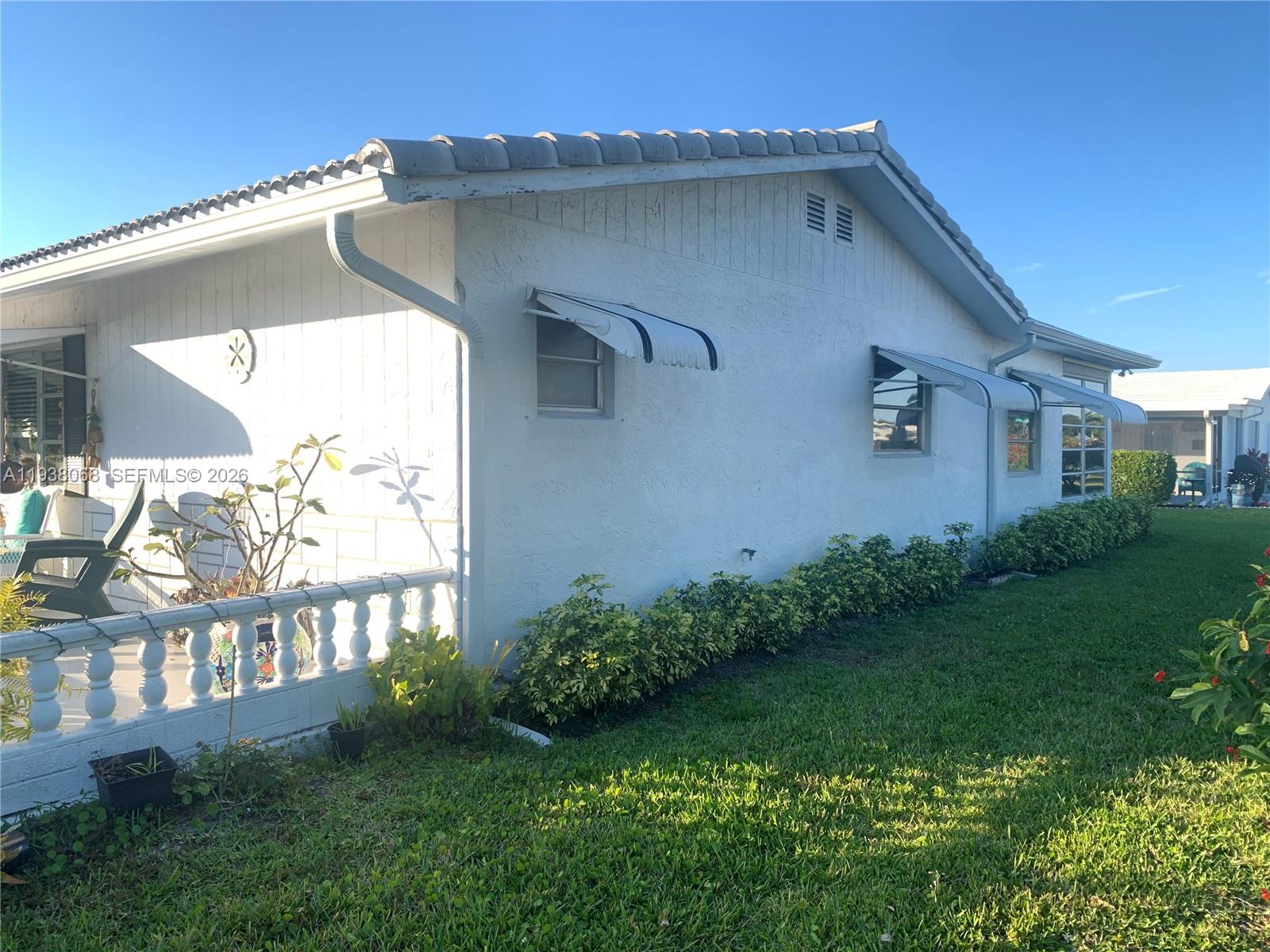 The exterior of a white house features a patio with a balustrade and window awnings — 1801 SW 22nd Way, Boynton Beach FL 33426, BOYNTON BEACH, FL