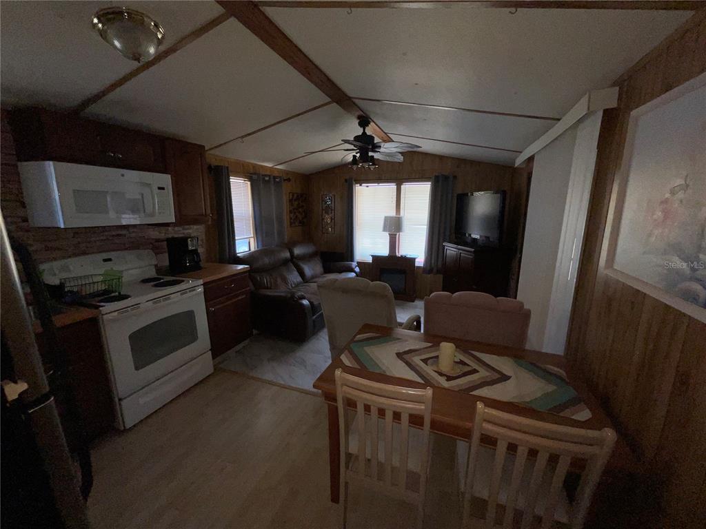 An open-concept living room and kitchen area with wood-paneled walls and a dining table — 38130 MCDONALD STREET UNIT 23, DADE CITY, FL
