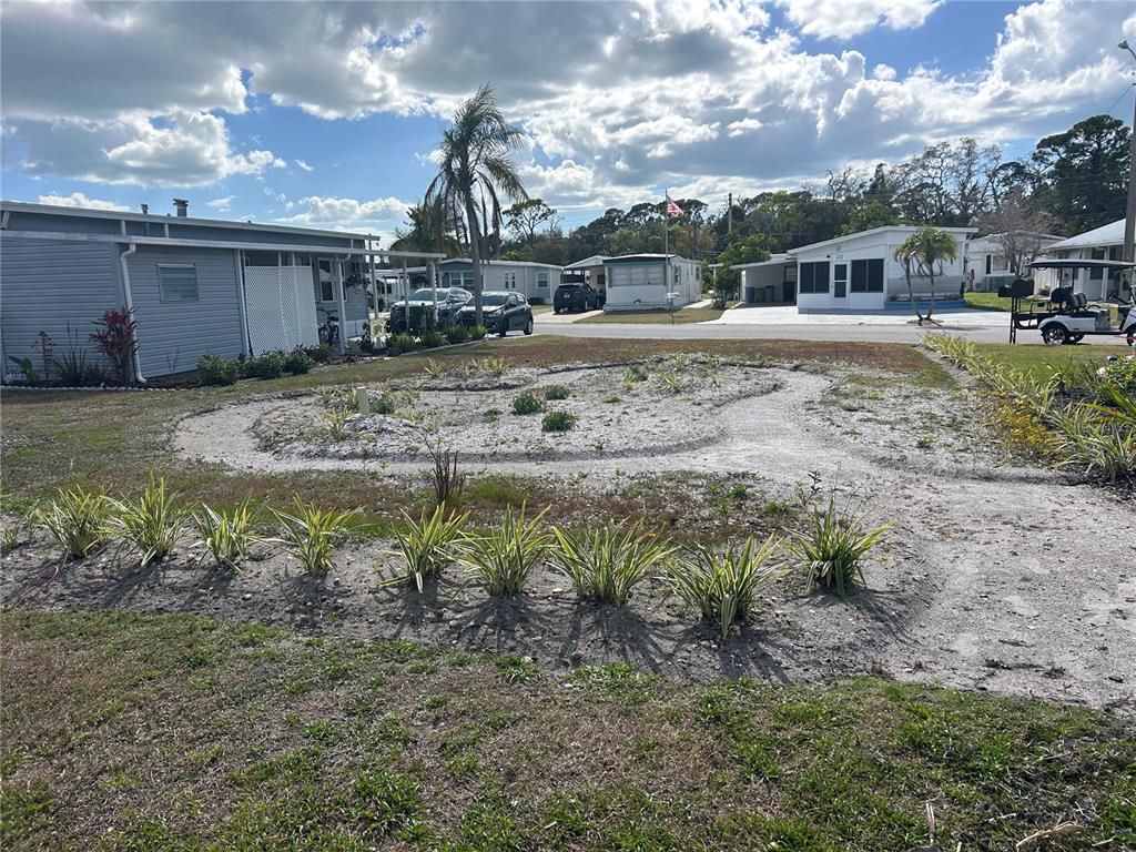 A sandy, landscaped yard with small plants sits in front of a mobile home community — 5254 PEBBLE BEACH AVENUE, SARASOTA, FL
