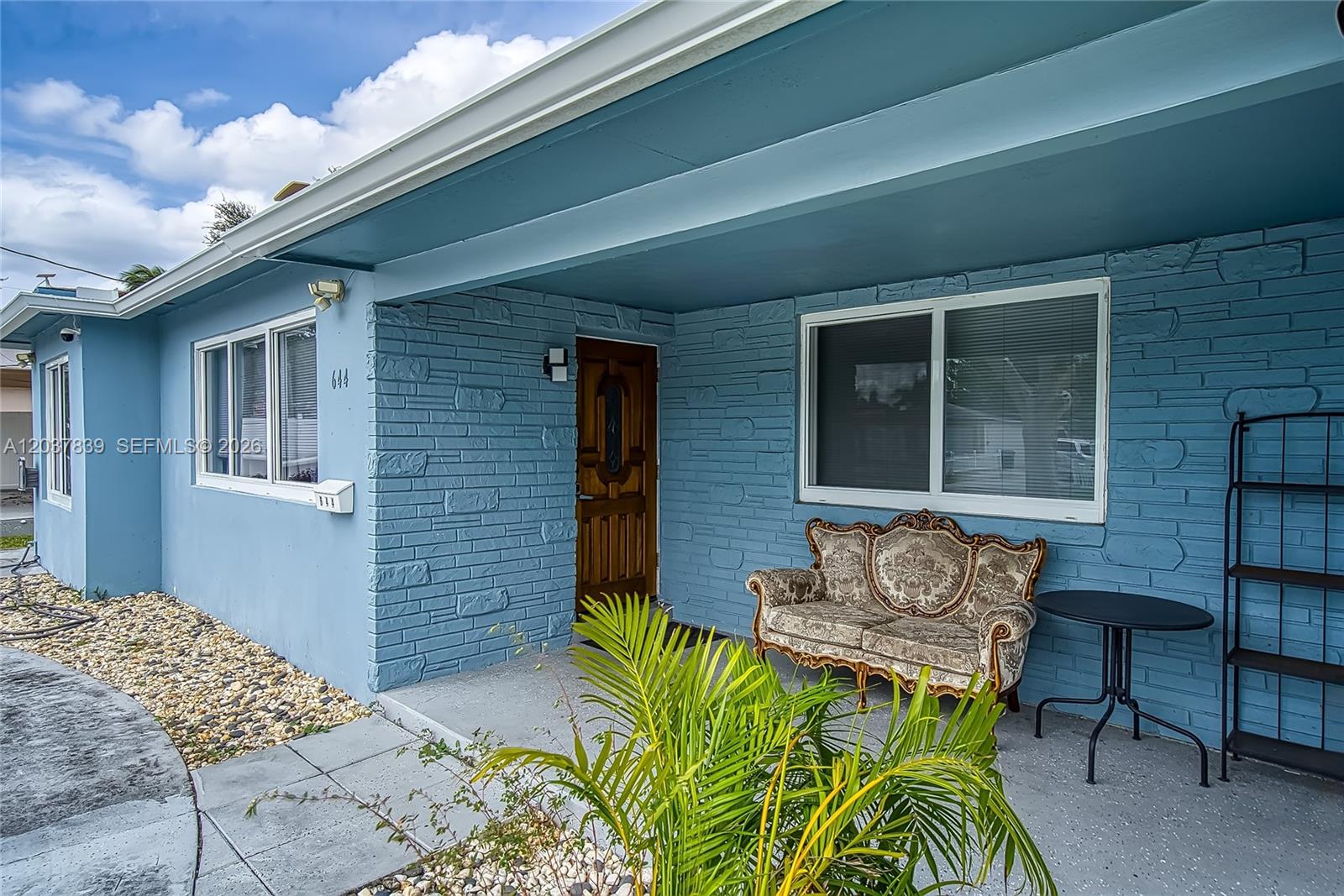 A blue brick house exterior features a front porch with a vintage sofa and table — 644 SW 7th Ct # 0, Hallandale Beach FL 33009, HALLANDALE BEACH, FL