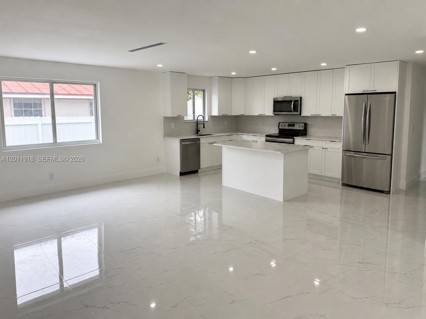 A modern kitchen features white cabinetry, stainless steel appliances, a center island, and tiled floors — 3536 NW 14th Ter, Miami FL 33125, MIAMI, FL