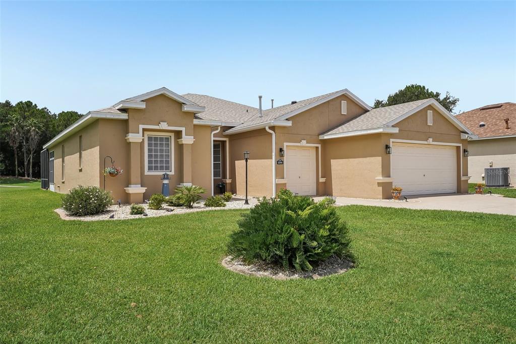 A single-story tan stucco house with a two-car garage and a landscaped front lawn — 1044 SW 159TH STREET, OCALA, FL