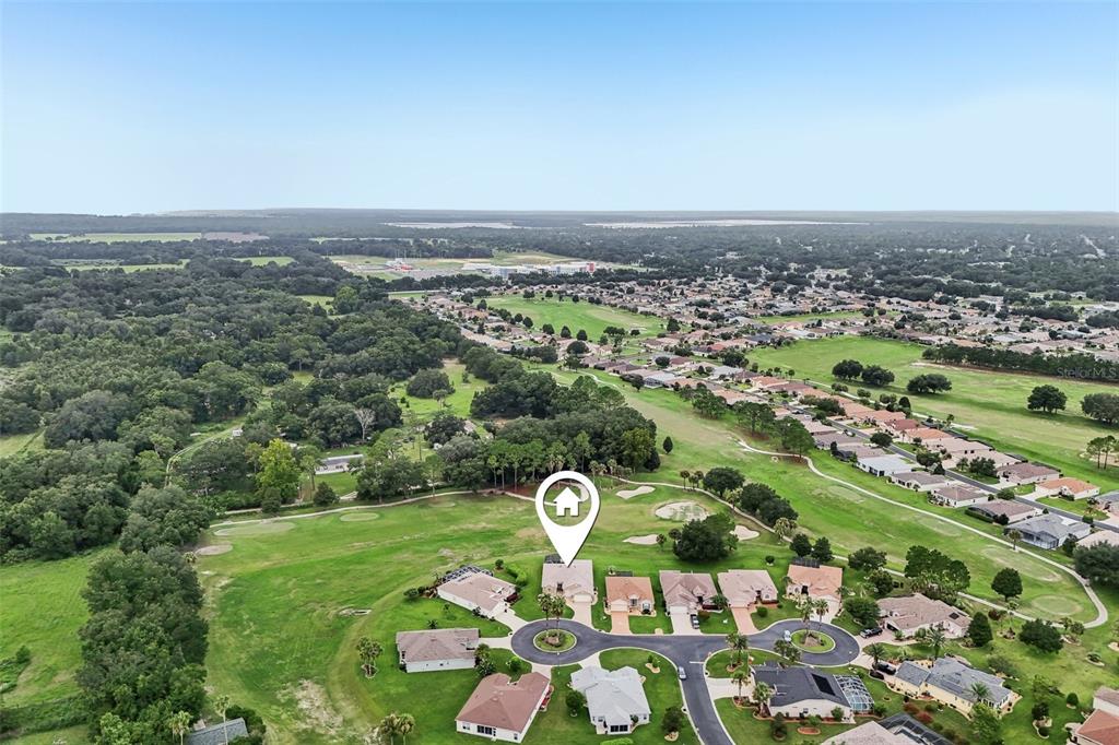 An aerial view shows a residential cul-de-sac surrounded by a golf course and wooded areas — 1044 SW 159TH STREET, OCALA, FL