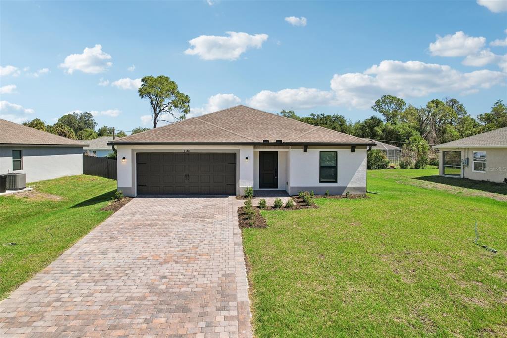 A single-story house with a brick paver driveway, a two-car garage, and a grassy yard — 3378 ESCOBAR LANE, NORTH PORT, FL