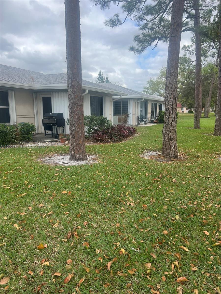The exterior of a single-story residential building features a grassy lawn and pine trees — 176 Cape Cod Circle # 0, Lake Worth FL 33467, LAKE WORTH, FL