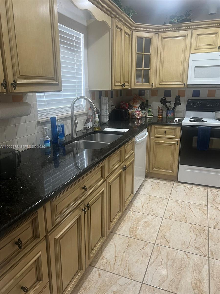 A kitchen features light wood cabinets, dark granite countertops, and light-colored tiled flooring — 176 Cape Cod Circle # 0, Lake Worth FL 33467, LAKE WORTH, FL