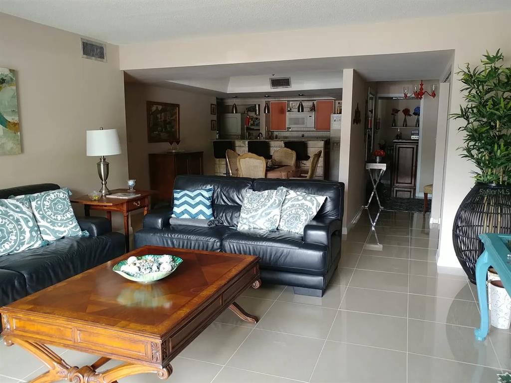 A living room with tile flooring, a black leather sofa, and an open kitchen area — 2225 HOLDEN AVENUE UNIT 109, ORLANDO, FL