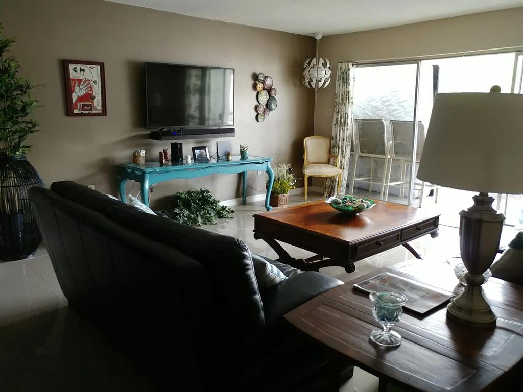 A living room features a dark leather sofa, a teal console table, and a wooden coffee table — 2225 HOLDEN AVENUE UNIT 109, ORLANDO, FL