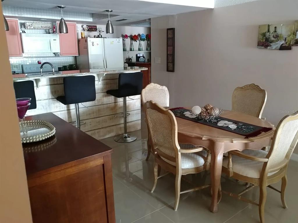 A dining area with a wooden table and chairs sits adjacent to a kitchen counter — 2225 HOLDEN AVENUE UNIT 109, ORLANDO, FL