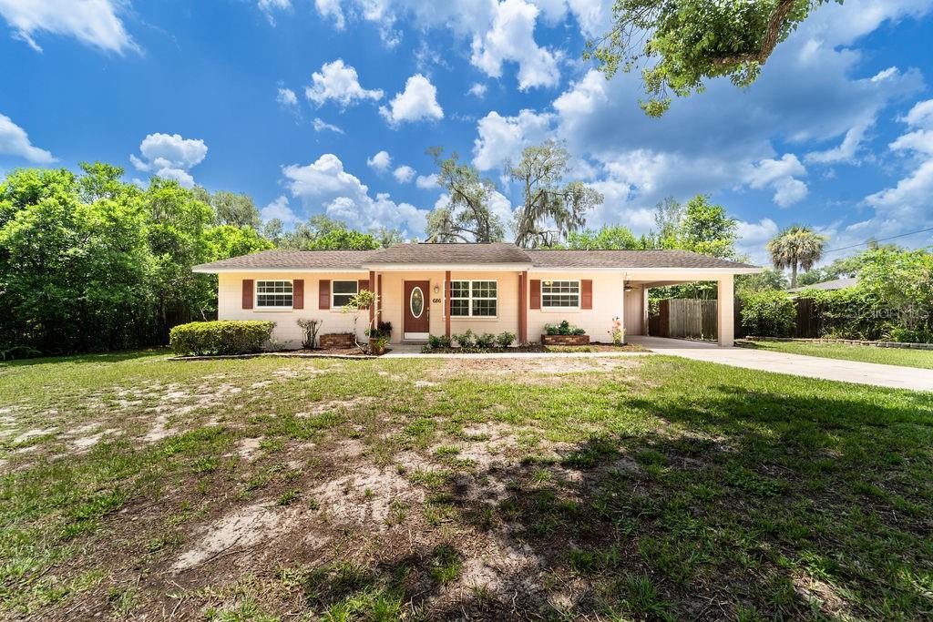 A single-story house with a beige exterior, brown shutters, and an attached carport — 686 E KENTUCKY AVENUE, DELAND, FL