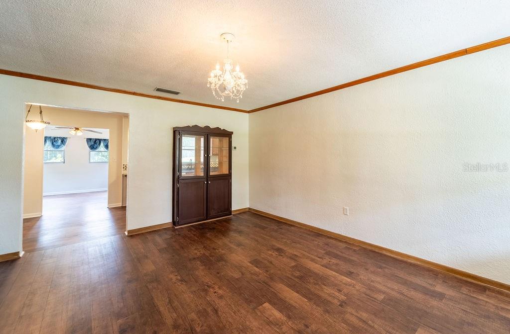 A dining room with wood-look flooring, a crystal chandelier, and a dark wood china cabinet — 686 E KENTUCKY AVENUE, DELAND, FL