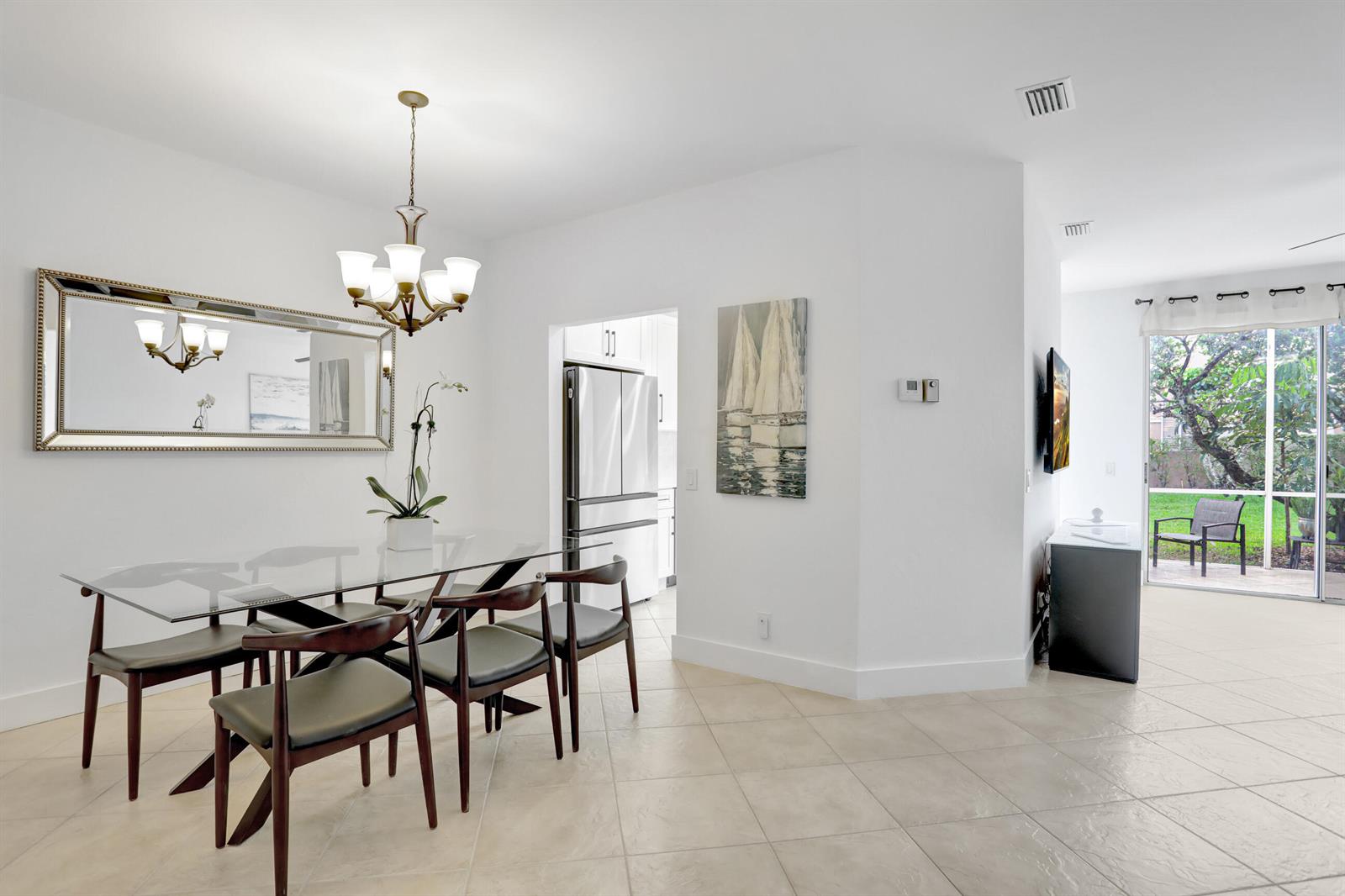 A dining room with a glass table, modern chairs, and a view of a patio — 6770 Via Regina, Boca Raton FL 33433, BOCA RATON, FL