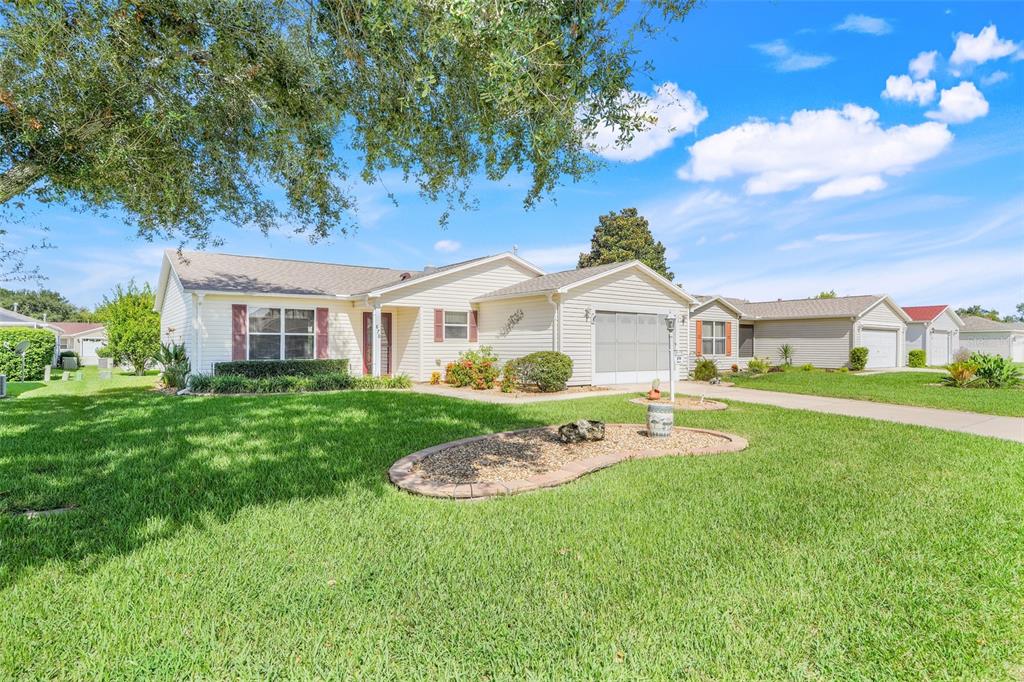 A single-story house with beige siding, a garage, and a landscaped front yard — 870 HENDERSON LANE, THE VILLAGES, FL