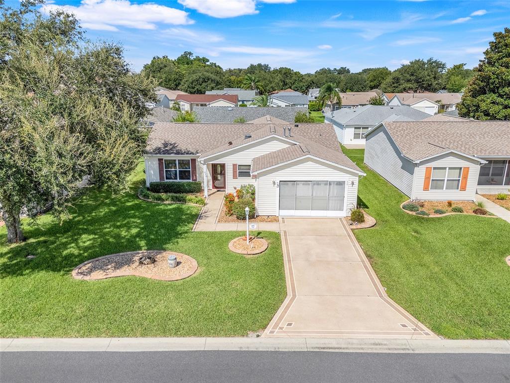 An aerial view of a single-story suburban house with a concrete driveway and green lawn — 870 HENDERSON LANE, THE VILLAGES, FL