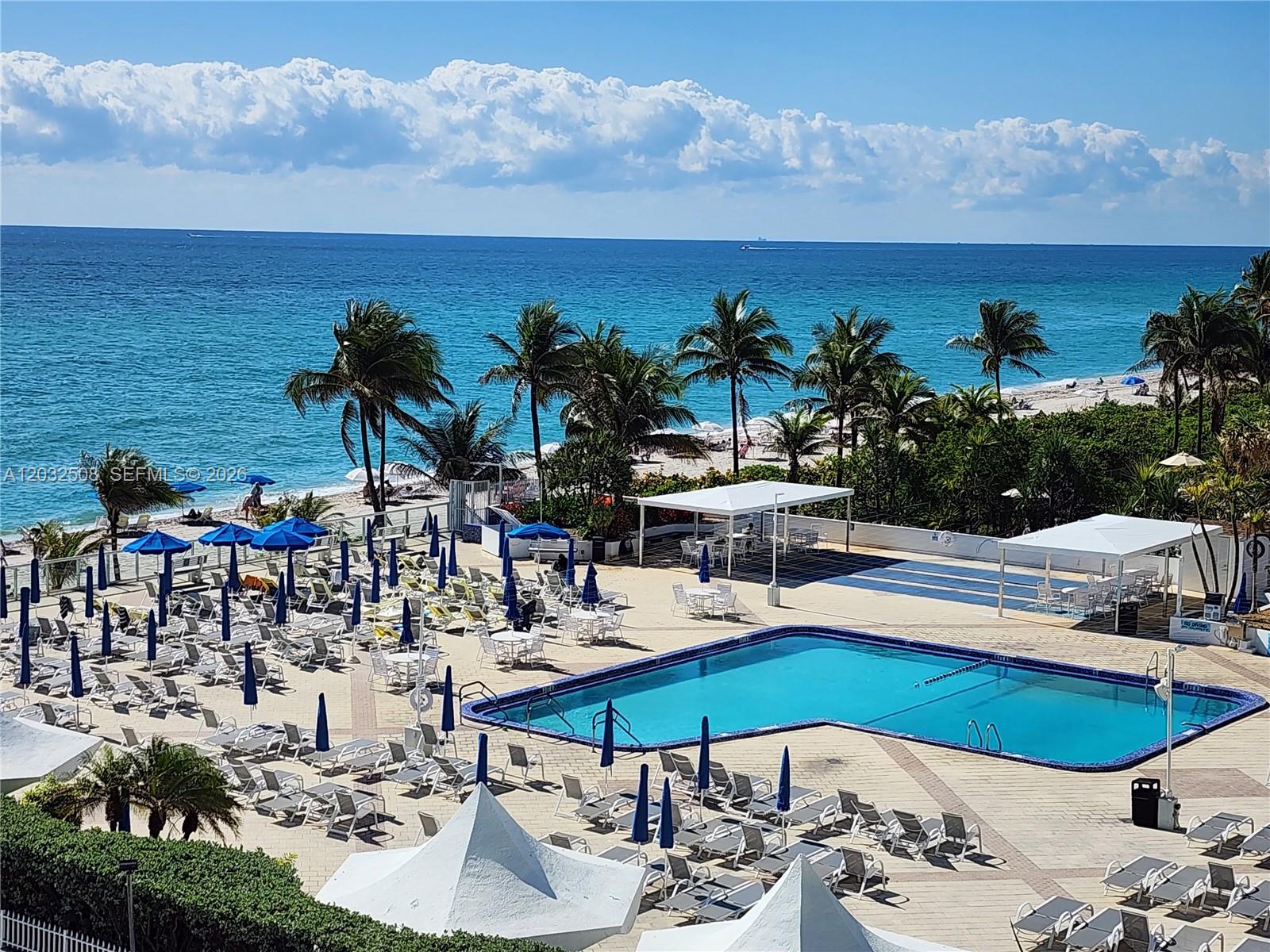 A swimming pool area with lounge chairs and umbrellas overlooks the ocean and beach — 2030 S Ocean Dr # 1405, Hallandale Beach FL 33009, HALLANDALE BEACH, FL