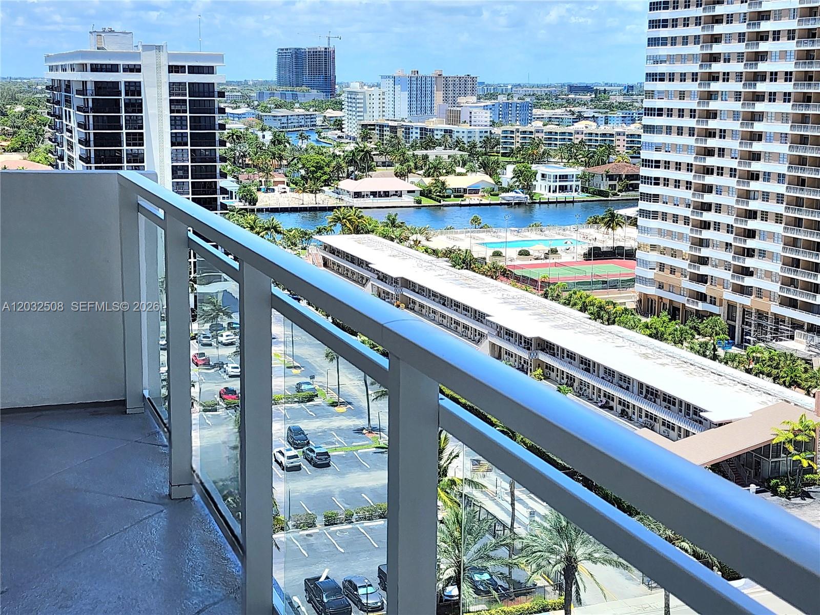 A high-angle view from a balcony overlooks a parking lot, a waterway, and city buildings — 2030 S Ocean Dr # 1405, Hallandale Beach FL 33009, HALLANDALE BEACH, FL