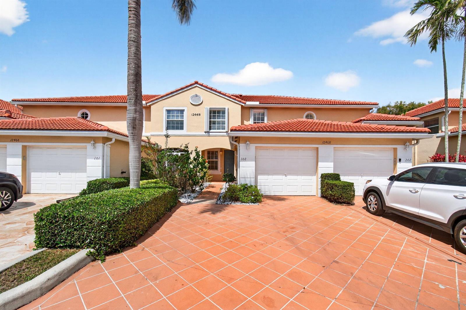 A multi-unit residential building with a tiled roof, garage doors, and a paved driveway — 12468 Crystal Pointe Drive # 102, Boynton Beach FL 33437, BOYNTON BEACH, FL