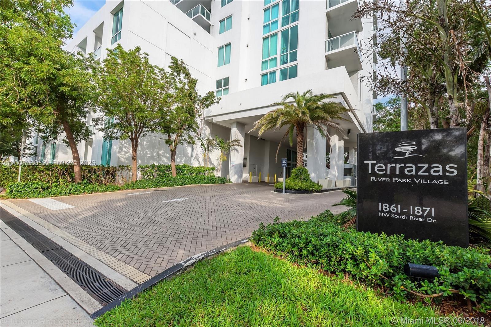 The exterior of a modern white residential building features a paved driveway and signage — 1871 NW S River Dr # 902, Miami FL 33125, MIAMI, FL