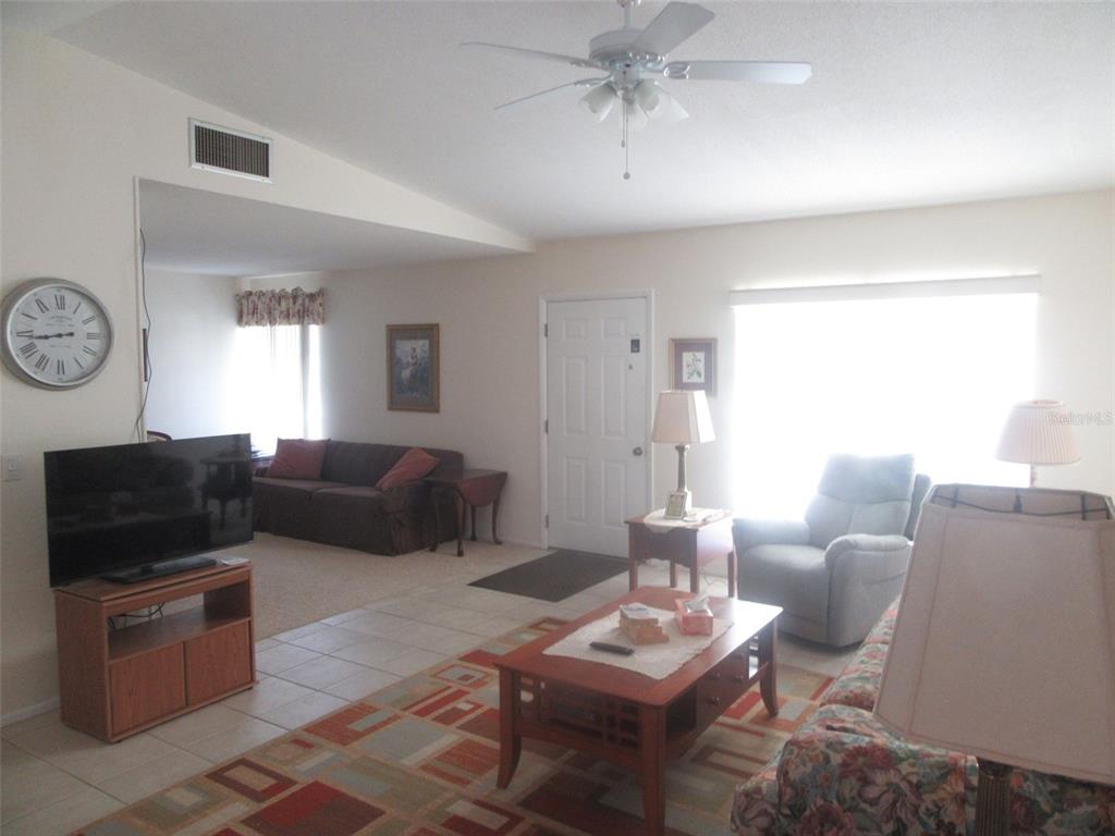 A living room features a ceiling fan, tile flooring, a television, and a seating area — 8158 FAY AVENUE, NORTH PORT, FL