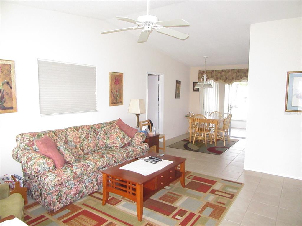 A living room with a floral sofa and coffee table leads to a dining area — 8158 FAY AVENUE, NORTH PORT, FL