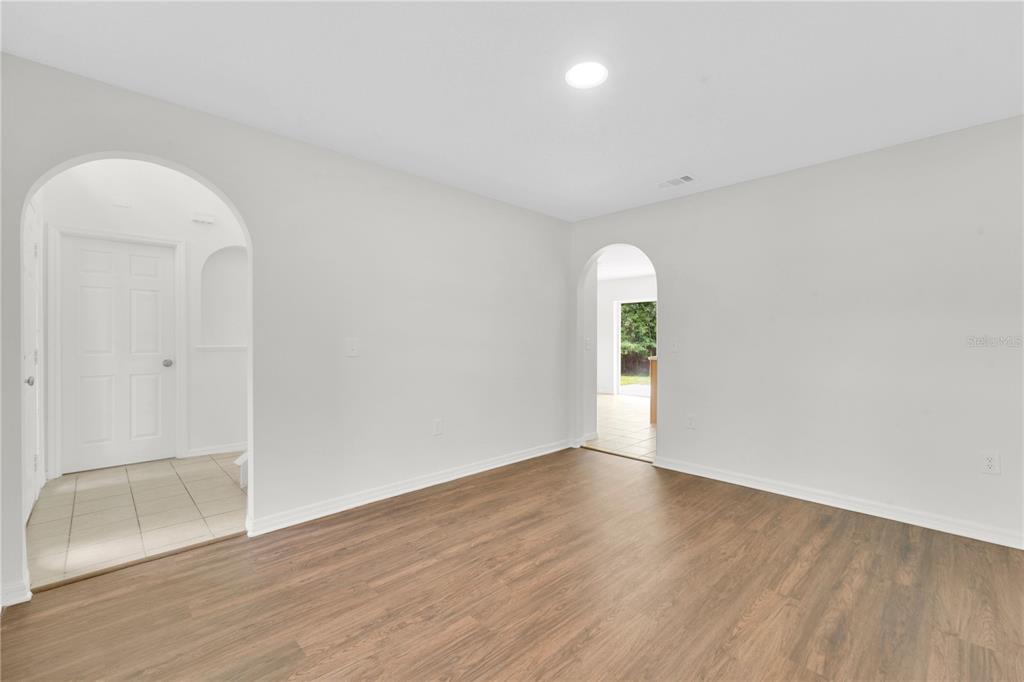 An empty room with wood-look flooring, white walls, and two arched doorways — 30131 RATTANA COURT, WESLEY CHAPEL, FL