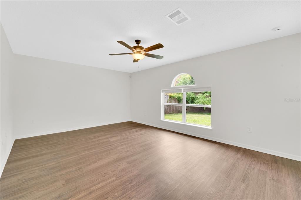 An empty room with light gray walls, wood-look flooring, a ceiling fan, and an arched window — 30131 RATTANA COURT, WESLEY CHAPEL, FL