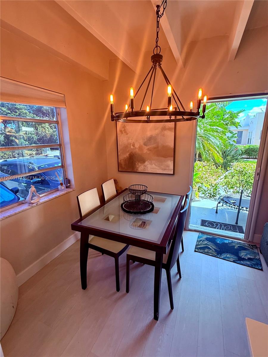 A dining area features a glass-topped table, a chandelier, and a sliding glass door — 115 S C St # 101, Lake Worth FL 33460, LAKE WORTH, FL