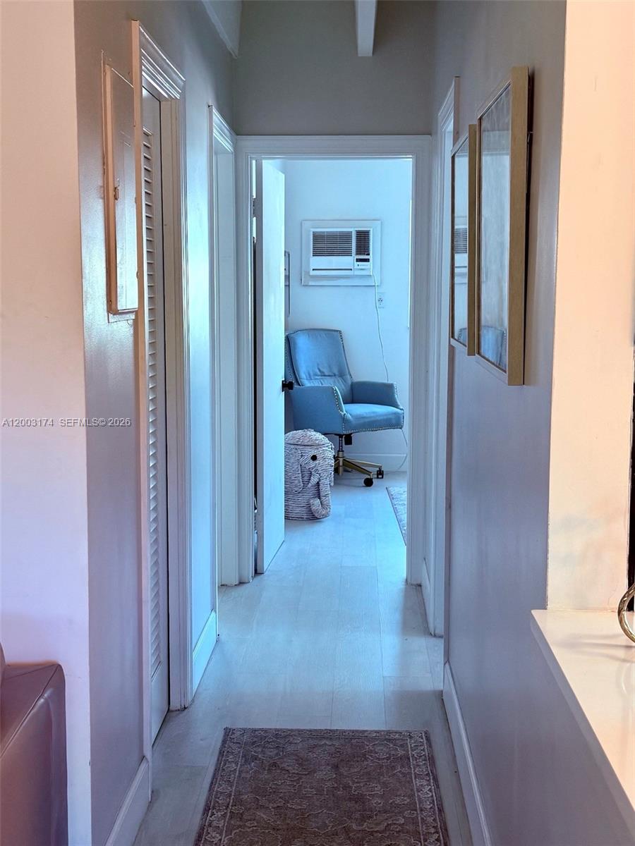 A hallway with light wood flooring leads to a room containing a blue chair — 115 S C St # 101, Lake Worth FL 33460, LAKE WORTH, FL