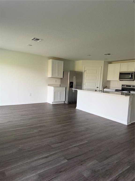 A kitchen with white cabinets, stainless steel appliances, and wood-look flooring in an open space — 1723 GRANDIOSE DRIVE, HAINES CITY, FL