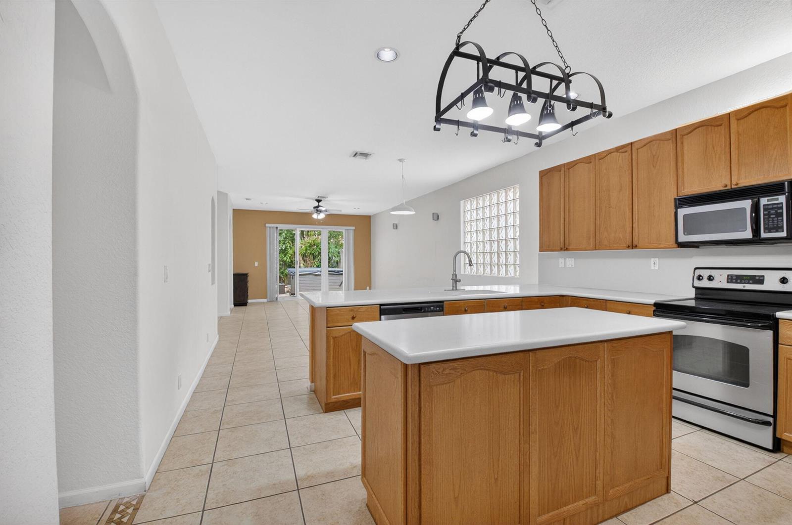 A kitchen with oak cabinets and a central island opens to a living area — 5049 Sancerre Circle, Lake Worth FL 33463, LAKE WORTH, FL