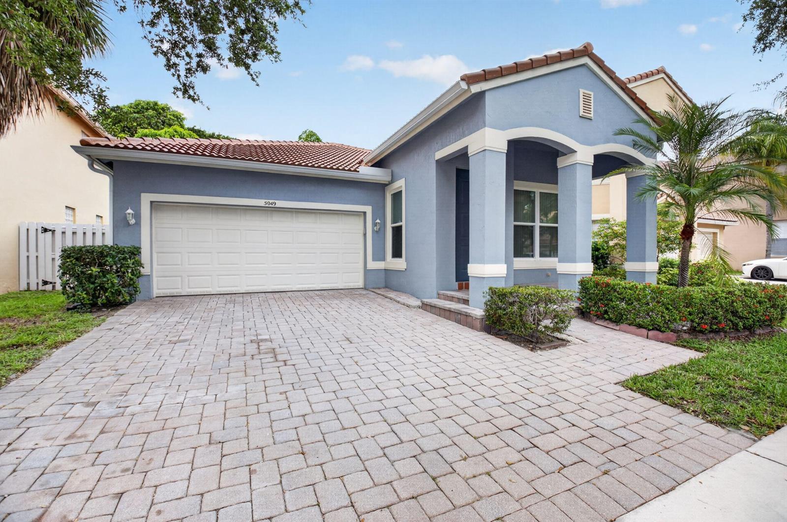 A blue single-story house with a tiled roof, a two-car garage, and a paved driveway — 5049 Sancerre Circle, Lake Worth FL 33463, LAKE WORTH, FL