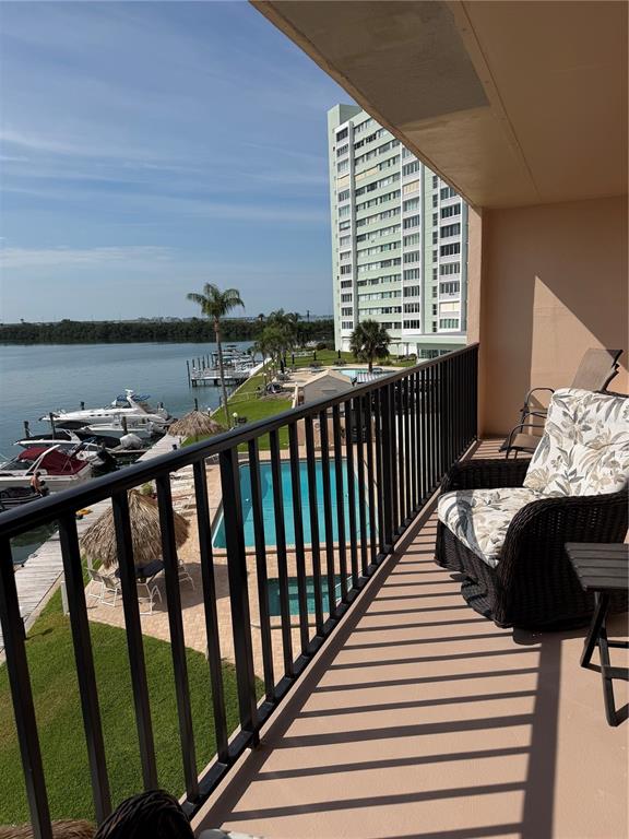 A balcony overlooks a swimming pool, a marina with boats, and a tall apartment building — 51 ISLAND WAY UNIT 306, CLEARWATER BEACH, FL