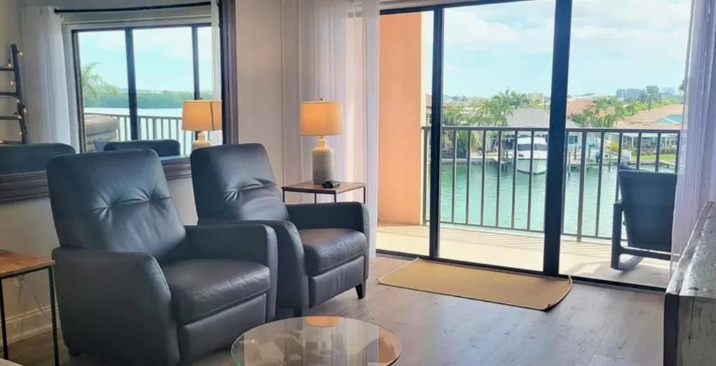 A living room with two dark armchairs overlooks a balcony and a marina — 51 ISLAND WAY UNIT 306, CLEARWATER BEACH, FL