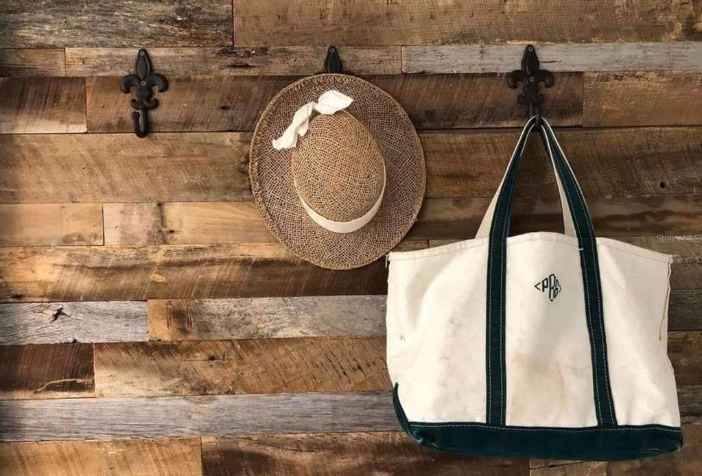 A straw hat and a canvas tote bag hang on fleur-de-lis hooks against a wood-paneled wall — 51 ISLAND WAY UNIT 306, CLEARWATER BEACH, FL