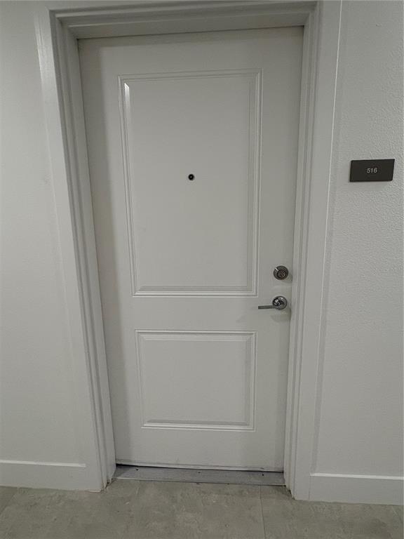 A white interior door with a peephole and silver hardware is labeled with number 516 — 5579 MILLENIA PARK BOULEVARD UNIT 516, ORLANDO, FL