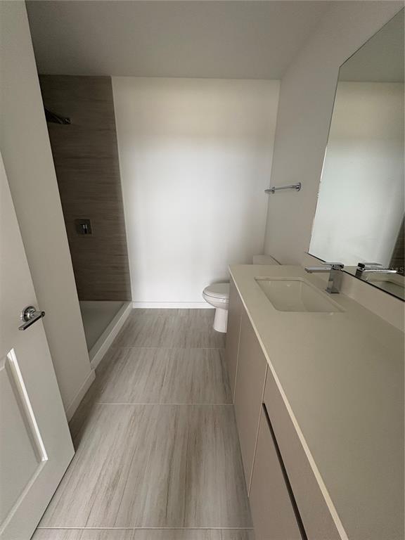 A modern bathroom features a walk-in shower, a single vanity, and light-colored tile flooring — 5579 MILLENIA PARK BOULEVARD UNIT 516, ORLANDO, FL