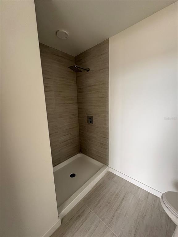 A bathroom features a walk-in shower with wood-look tile walls and a white shower pan — 5579 MILLENIA PARK BOULEVARD UNIT 516, ORLANDO, FL