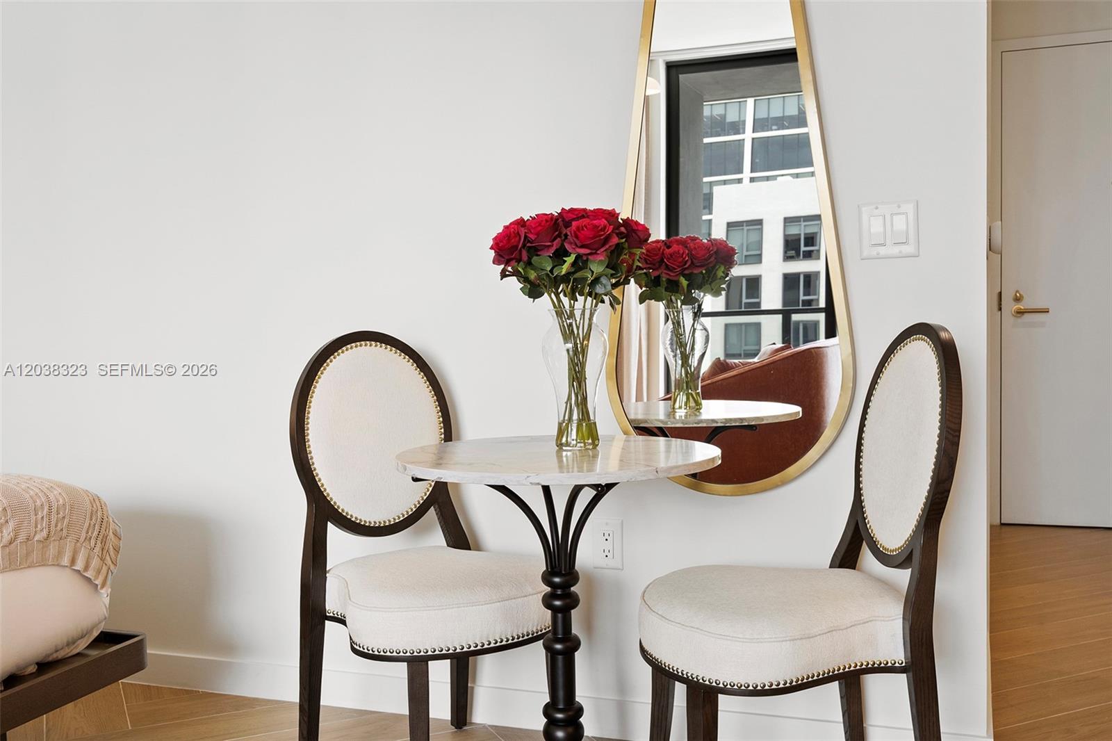 A small bistro table with two chairs and a mirror sits in a room — 2700 NW 2nd Ave # 644, Miami FL 33127, MIAMI, FL