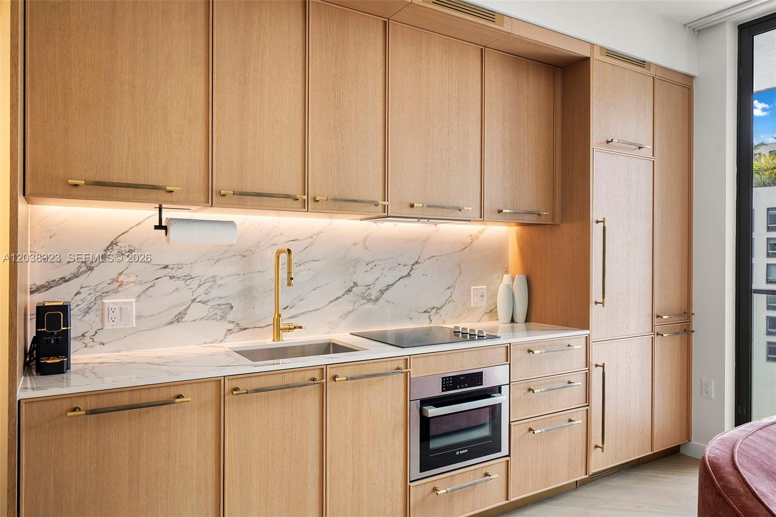 A modern kitchen features light wood cabinetry, a marble backsplash, and gold-toned hardware — 2700 NW 2nd Ave # 644, Miami FL 33127, MIAMI, FL