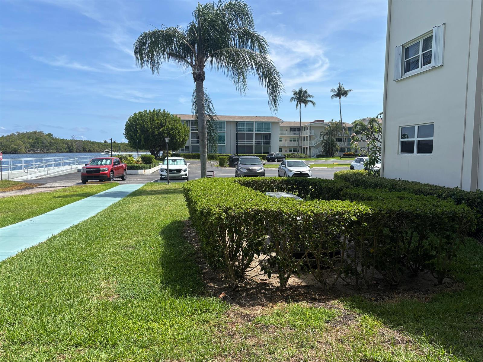 A parking lot with cars and a palm tree sits beside a building and lawn — 170 Horizons E # 110, Boynton Beach FL 33435, BOYNTON BEACH, FL