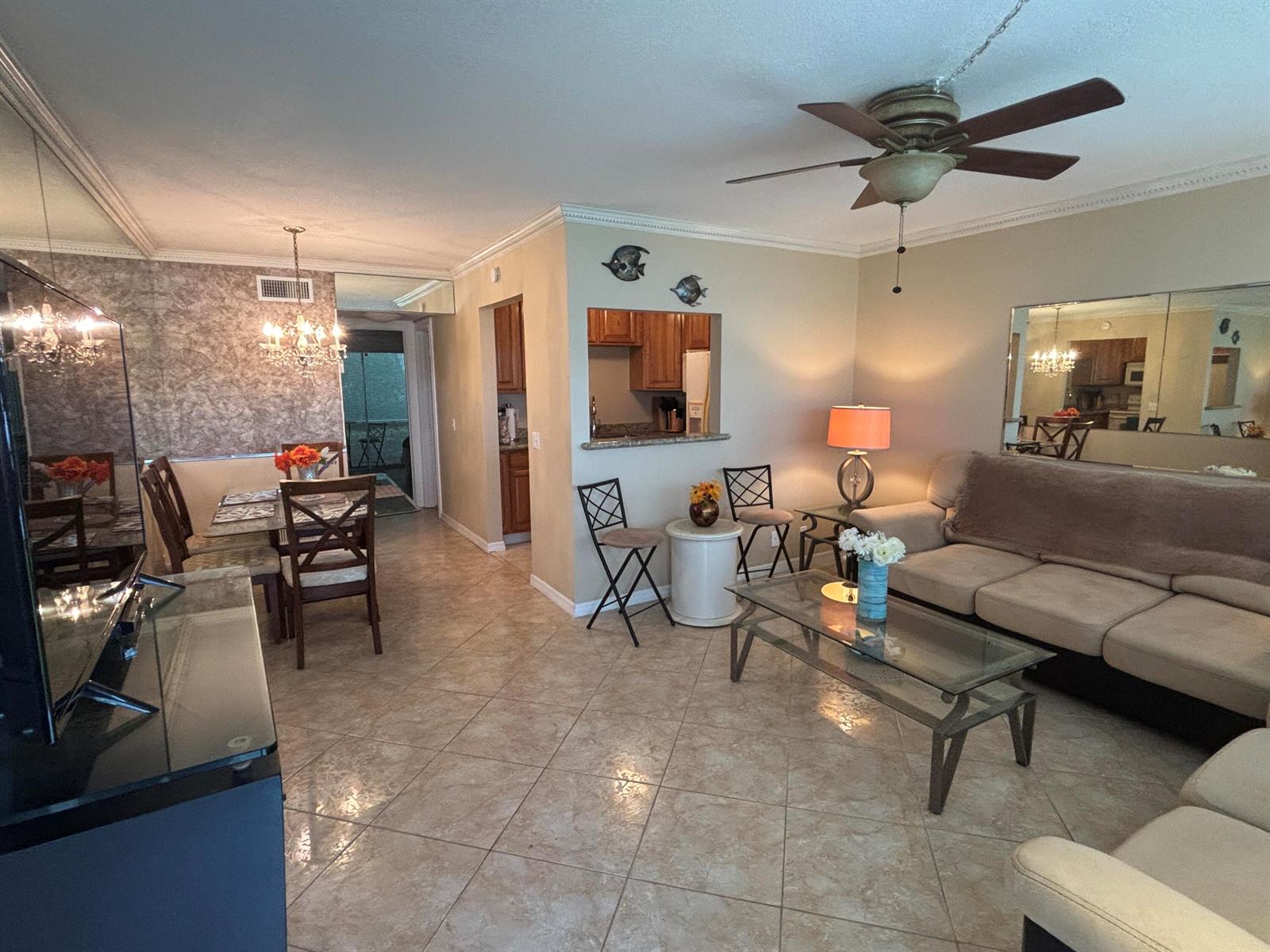 An open-concept living and dining area features tile flooring, a ceiling fan, and mirrored walls — 170 Horizons E # 110, Boynton Beach FL 33435, BOYNTON BEACH, FL