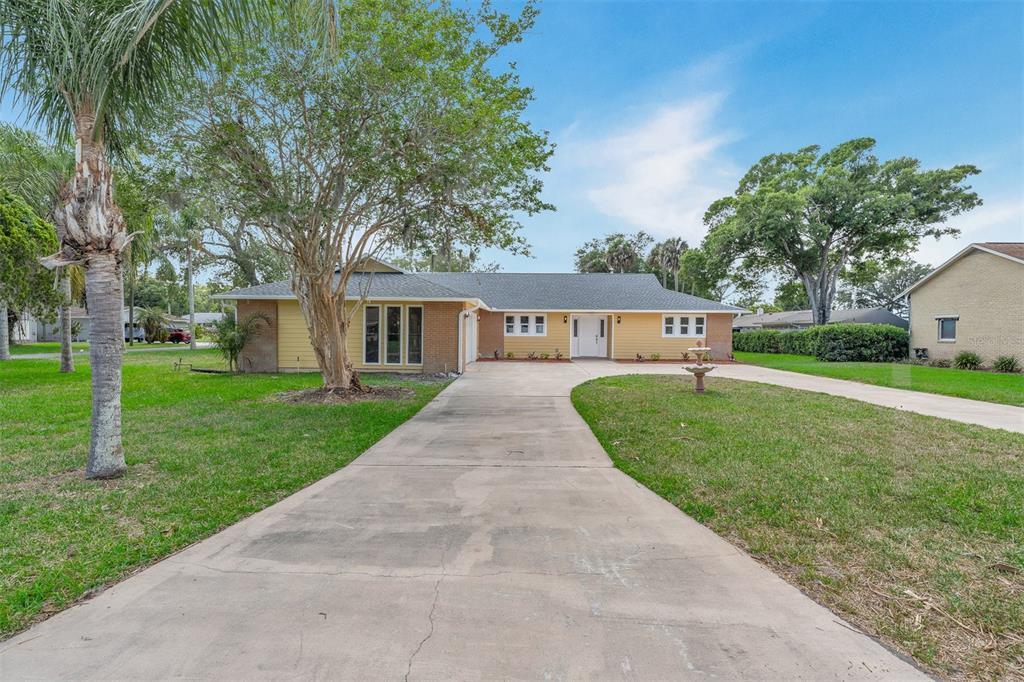 A yellow single-story house with a long concrete driveway and a large front yard — 716 GREEN RD, NEW SMYRNA BEACH, FL