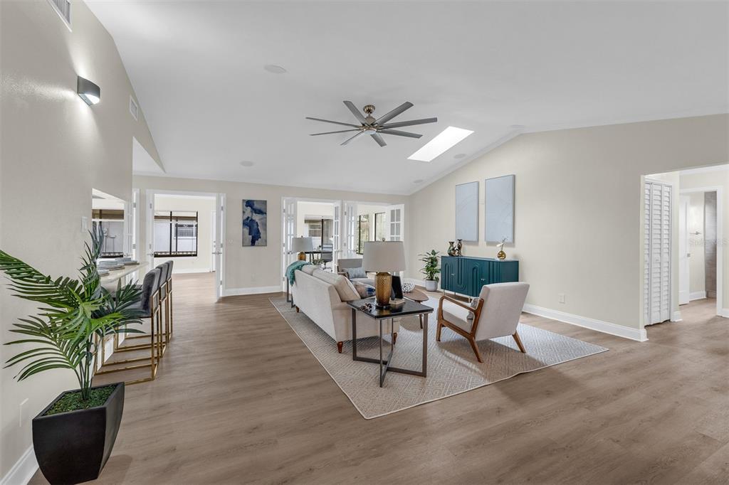 A living room features light wood-look flooring, a ceiling fan, and a neutral color palette — 716 GREEN RD, NEW SMYRNA BEACH, FL
