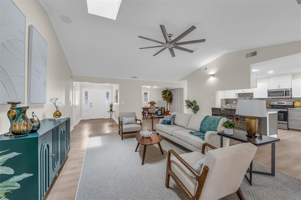 An open-concept living room features a vaulted ceiling, light wood floors, and a modern kitchen — 716 GREEN RD, NEW SMYRNA BEACH, FL